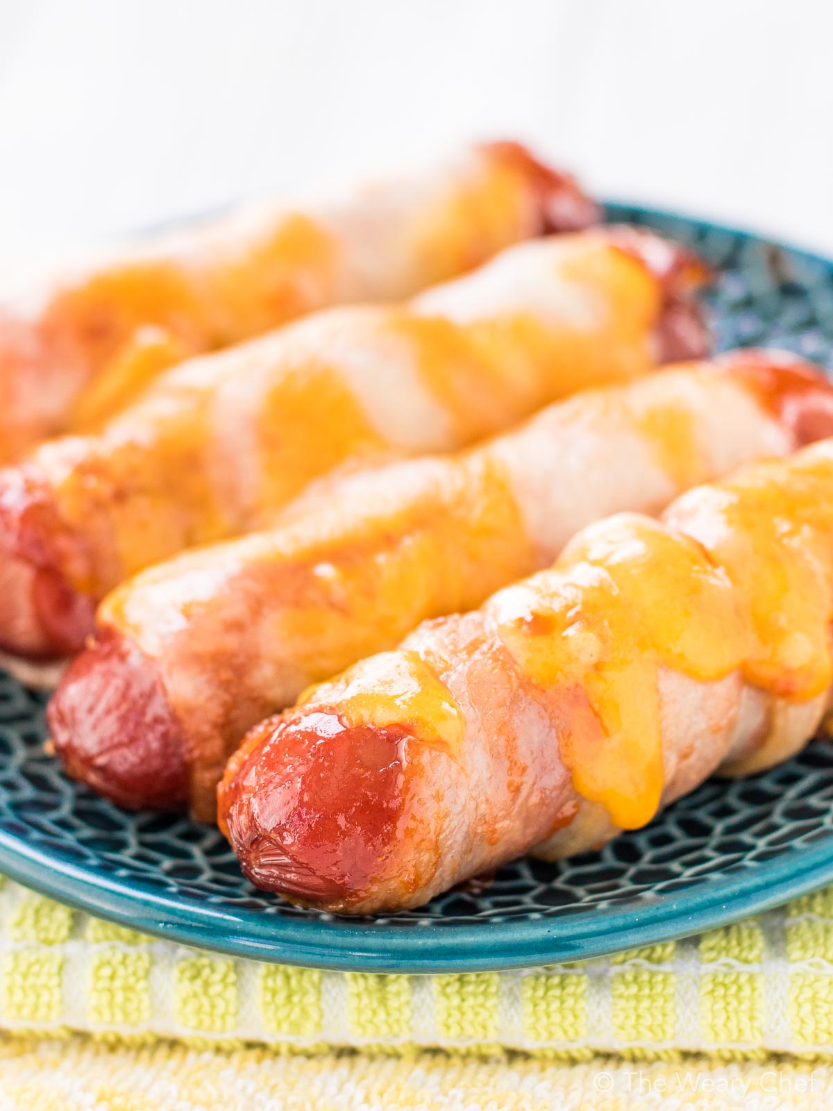 These cheesy BBQ Bacon Wrapped Hot Dogs are fun and easy to make. Perfect for the oven or grill. Serve them on buns or on their own for a lower carb treat!