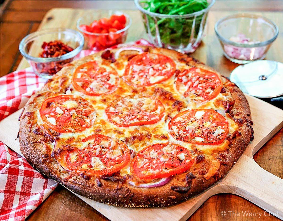 Bite into this BLT pizza loaded with a bacon, red onion, fresh tomatoes, arugula, cheeses, and a garlic-mayo sauce. It's your favorite sandwich turned into a chewy pizza! #blt #pizza #bacon