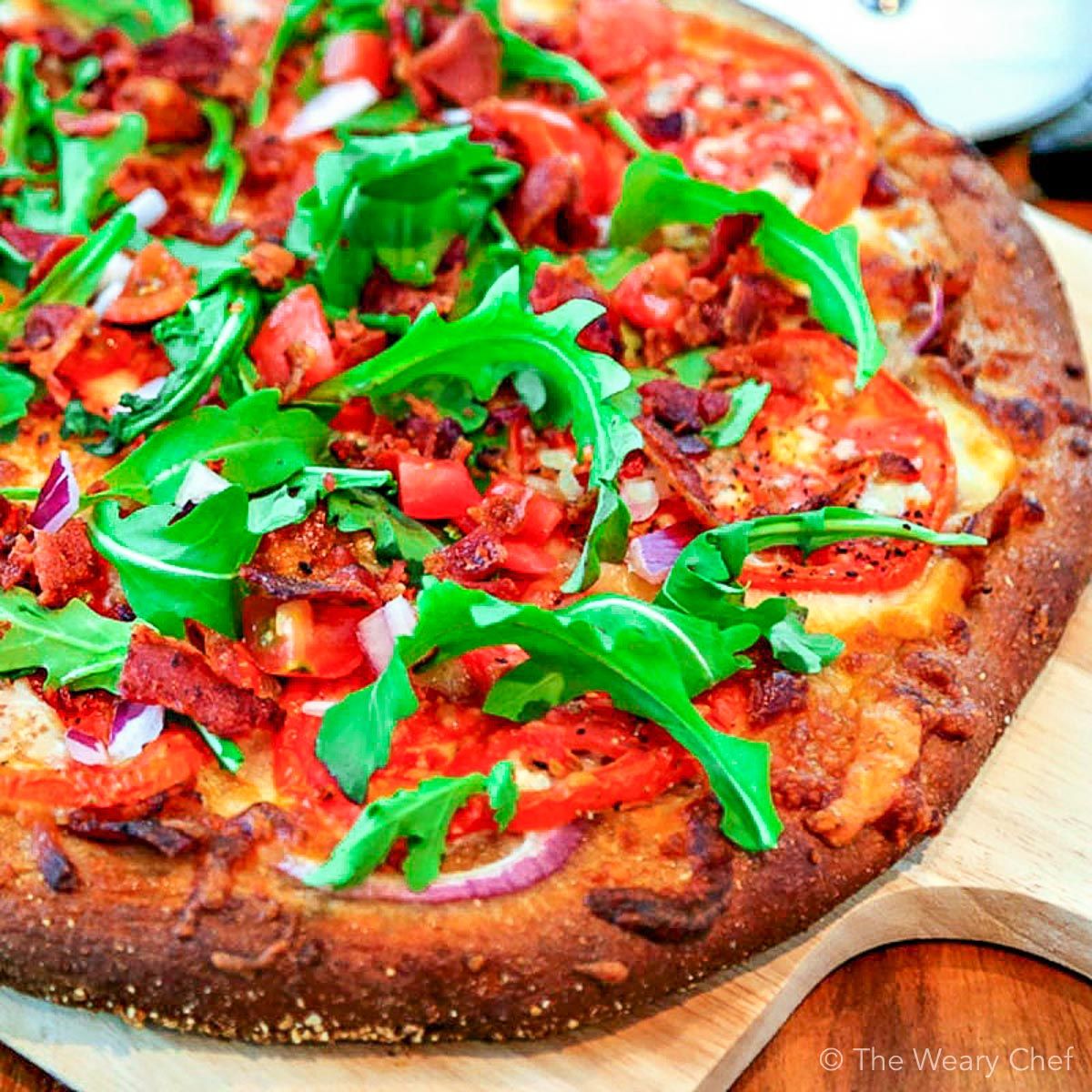 Bite into this BLT pizza loaded with a bacon, red onion, fresh tomatoes, arugula, cheeses, and a garlic-mayo sauce. It's your favorite sandwich turned into a chewy pizza! #blt #pizza #bacon