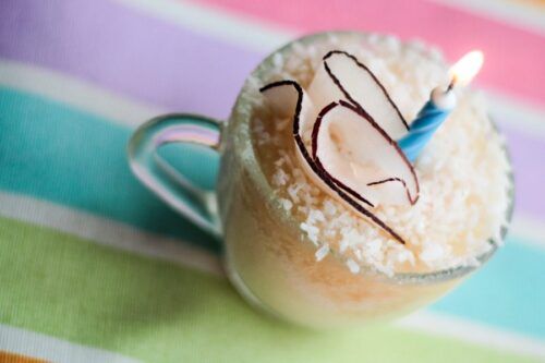 A dainty vanilla mug cake with a candle on top.