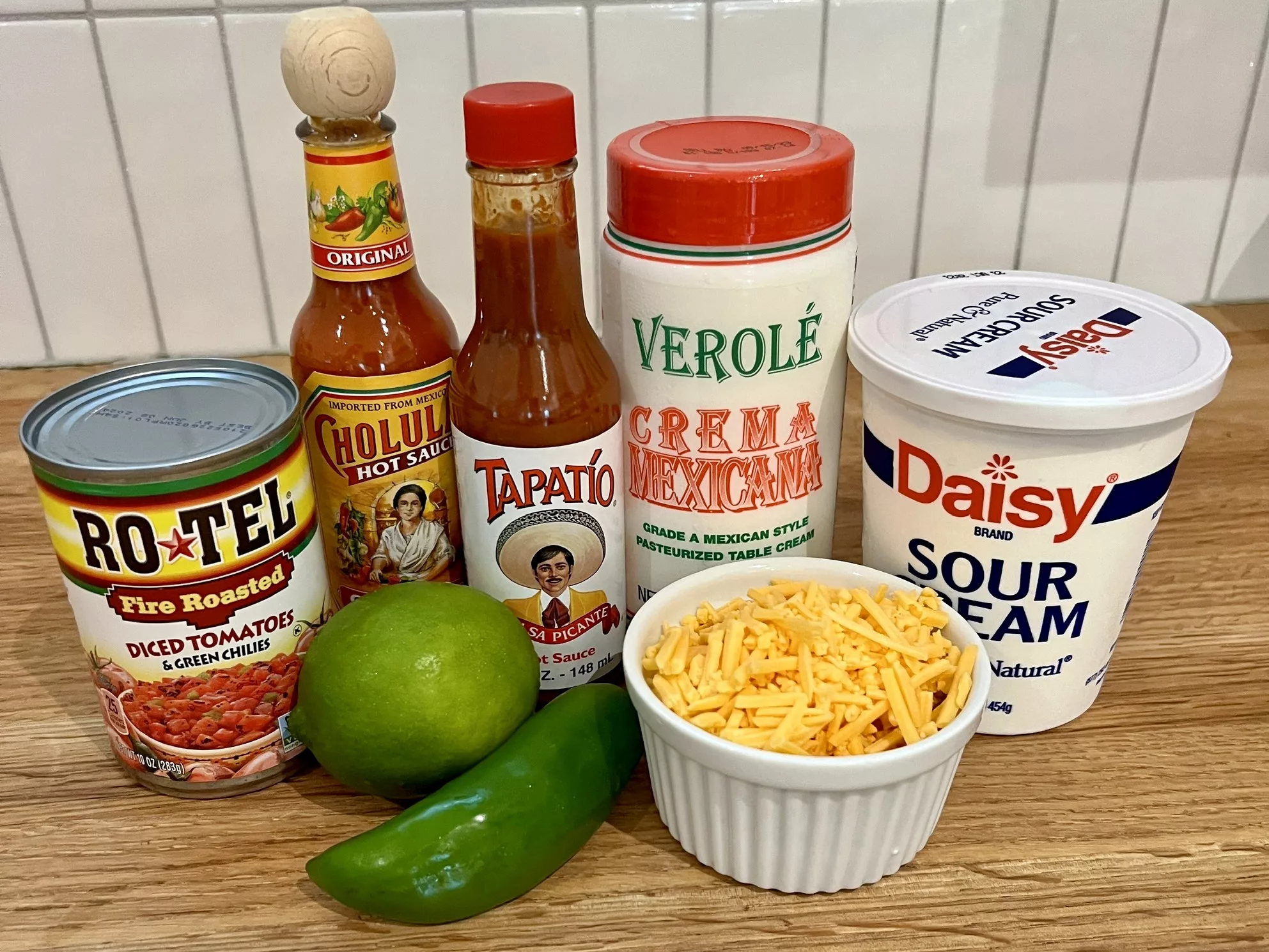 ingredients in cheesy queso inspired sour cream dip include sour cream, cheddar cheese, jalapeno, lime, hot sauce, hotel tomatoes.