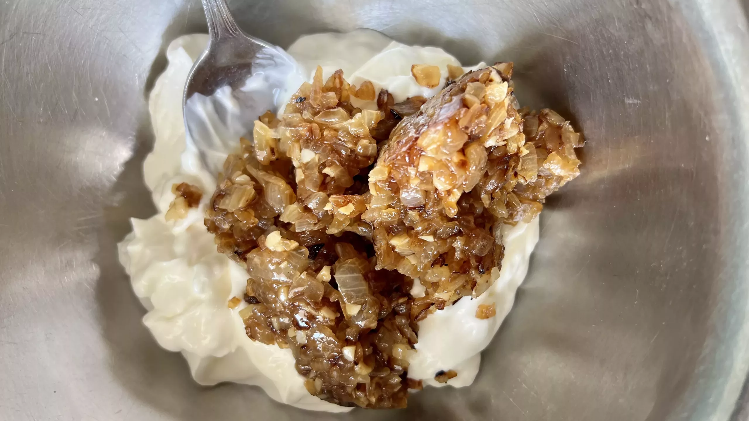 beautifully caramelized onions being mixed together with sour cream